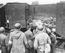 Des soldats américains découvrirent ces wagonnets chargés de détenus morts à l’extérieur du camp de Dachau. Ici, ils forcent des enfants allemands - soupçonnés d’être des membres des jeunesses hitlériennes (HJ) - à affronter l’atrocité. Dachau, Allemagne, 30 avril 1945.