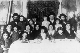 Portrait of the Ehrlich family seated around the family table. Munkacs, Czechoslovakia, 1930.
Among those pictured is Elizabeth Ehrlich (later Roth) standing in the middle of the back row in a light dress, and Rella Ehrlich (front row, second from the right). Elizabeth was born in Munkacs. In 1944 she was confined to the ghetto there before being deported with her family to Auschwitz. She was later transferred to a camp in Bydogszcz, Poland, and from there to the Stutthof concentration camp.