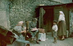A color photograph of Eva Justin interviewing a Romani woman interned in a "Gypsy camp." Vienna, Austria, 1940.
During the Nazi era, Dr. Robert Ritter was a leading authority on the racial classification of people pejoratively labeled “Zigeuner” (“Gypsies”). Ritter’s research was in a field called eugenics, or what the Nazis called “racial hygiene.” Ritter worked with a small team of racial hygienists. Among them were Eva Justin and Sophie Ehrhardt. Most of the people whom Ritter studied and classified as Zigeuner were German Roma called Sinti. Sinti are a subgroup of Romani peoples. 
In 1935, municipal authorities across Nazi Germany began to force Romani families to move into Zigeunerlager (“Gypsy camps”). Eventually, these camps were centralized under the authority of the Nazi Kripo (criminal police). Ritter and his team regularly examined the individuals in these camps. They sometimes used threats or bribes to force people to cooperate. The creation of these camps was one of the Nazis’ early steps toward the genocide of Romani peoples. Many Romani victims were later deported to concentration camps, ghettos, or killing centers. 
Source Record ID: Bild 146/87/108/15