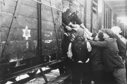 Jews load a barrel of water onto a deportation train in Skopje. [LCID: 79617]