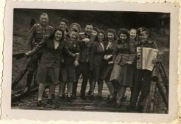 SS female auxiliaries (Helferinnen) run down a ramp in Solahütte to the music of an accordion.
From Karl Höcker's photograph album, which includes both documentation of official visits and ceremonies at Auschwitz as well as more personal photographs depicting the many social activities that he and other members of the Auschwitz camp staff enjoyed. These rare images show Nazis singing, hunting, and even trimming a Christmas tree. They provide a chilling contrast to the photographs of thousands of Hungarian Jews deported to Auschwitz at the same time. 