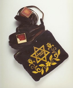 Seperangkat tefilin dalam sebuah tas bordir. Tefillin adalah benda ritual yang dikenakan oleh kaum Yahudi saat sembahyang pagi setiap hari. Benda ini ditemukan pada mayat korban mars kematian, yang dikubur dekat Regensburg, Jerman.