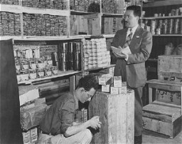 Morris Laub (right), American Jewish Joint Distribution Committee director for Cyprus, reviews supplies sent for the 12,000 Jews still interned on the island. Cyprus, December 9, 1948.