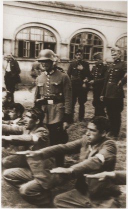 Members of the German Order Police publicly humiliate a group of Jews by forcing them to perform exercises, 1939–1940. Sosnowiec, in German-occupied Poland.