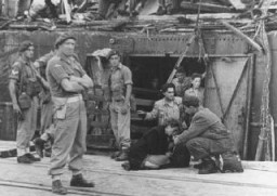 Une femme épuisée, passagère de l' "Exodus 1947", le célèbre bateau de réfugiés, se voit offrir une boisson avec à ses côtés des soldats britanniques. Les Anglais ont forcé les passagers à retourner en Europe. Haïfa, Palestine, 19 juillet 1947.