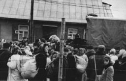 Jewish men, women, and children boarding trucks during deportations from the Kovno ghetto. [LCID: 81087]