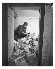 A US soldier inspects piles of Nazi books, including Mein Kampf, that were found in a German school. As part of their denazification policies, Allied authorities purged German libraries, bookstores, and schools of Nazi propaganda. Aachen, Germany, May 2, 1945.