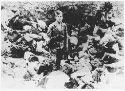 A Ustasa (Croatian fascist) guard stands amid corpses at the Jasenovac concentration camp, Yugoslavia, 1942. [LCID: 64309]