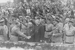 Adolf Hitler greets Reich Bishop Ludwig Mueller at a Nazi Party Congress. Roman Catholic Abbot Alban Schachleiter stands between Hitler and Mueller. Nuremberg, Germany, September 1934.