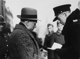 A Polish policeman checks the papers of a Jewish resident of the Warsaw ghetto. [LCID: 5435]