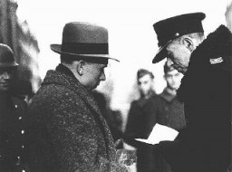 A Polish policeman checks the papers of a Jewish resident of the Warsaw ghetto. Warsaw, Poland, February 1941.