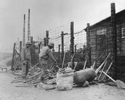  African American soldiers, members of a company of the US Third Army, inspect tools used by a forced-labor battalion. [LCID: 01724]