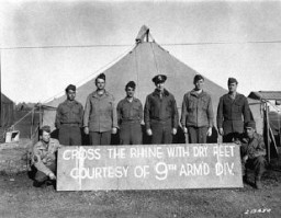 The commanding general of the 9th Armored Division (third from right), and members of the division who won the Distinguished Service Cross pose with the sign placed on the Ludendorff Bridge after its capture. US Army Signal Corps photograph taken by W. Spangle on September 18, 1945, several months after the bridge was captured.