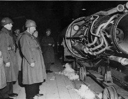 Members of a US congressional committee investigating German atrocities view a V-2 rocket on the assembly line of an underground factory at the Dora-Mittelbau concentration camp, near Nordhausen. Germany, May 1, 1945.