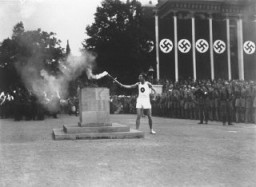 3000人のランナーによりギリシャから運ばれた聖火を、第11回夏季オリンピック大会が開幕するベルリンのオリンピック会場で点灯する最後のリレー走者。1936年8月、ドイツ、ベルリン。