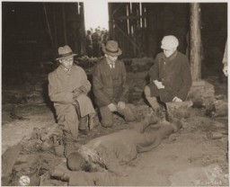 ثلاثة محافظين أمام جثث سجناء حُرقت في مخزن من قبل قوات الأمن الخاصة خلال مسيرات الموت من مدينة روتليبيرودي, محتشد فرعي لدورا ميتلباو. غاردليغن, 18 أبريل 1945.