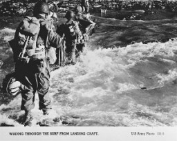 US troops wade through the surf on their arrival at the Normandy beaches on D-Day. Normandy, France, June 6, 1944.
