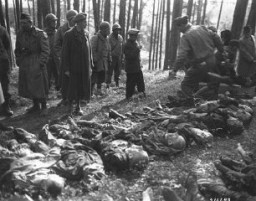 A Hungarian Jewish youth identifies the body of his father, who was shot by the SS during a death march from Flossenbürg. Members of the US military prepare the victims' burial. Neunburg, Germany, April 25, 1945.