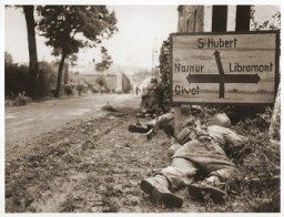 US soldiers of the 8th Infantry Regiment seek cover behind hedges and signs to return fire to German forces holding the town of Libin. Belgium, September 7, 1944.