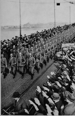 During the remilitarization of the Rhineland, German civilians salute German forces crossing the Rhine River in open violation of ... [LCID: 08060]