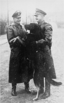 Two SS officers and a guard dog in the Janowska concentration camp. [LCID: 69984]