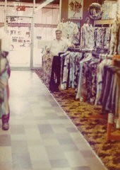 Aron standing in Howard's men's clothing store (named for his eldest son) at 9125 Commercial Avenue in Chicago. He opened the store in 1949 and owned it for 30 years. Chicago, Illinois, early 1970s.