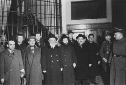 Members of the German Security Service (SD) stand with members of the Jewish Community Council in the Jewish community building, where the Germans conducted interrogations. Warsaw, Poland, October-November 1939.