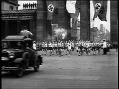 In 1933, Nazi Party leader Adolf Hitler became chancellor of Germany and quickly turned the nation's fragile democracy into a one-party dictatorship. Police rounded up thousands of political opponents, detaining them without trial in concentration camps. The Nazi regime also put into practice racial policies that aimed to "purify" and strengthen the Germanic "Aryan" population. A relentless campaign began to exclude Germany's one-half million Jews from all aspects of German life. For two weeks in August 1936, Adolf Hitler camouflaged his antisemitic and expansionist agenda while Berlin hosted the Summer Olympic Games. Hoping to impress the many foreign visitors who were in Germany for the games, Hitler authorized a brief relaxation in anti-Jewish activities (including even the removal of signs barring Jews from public places). The games were a resounding propaganda success for the Nazis. They presented foreign spectators with the image of a peaceful and tolerant Germany. Here, Hitler formally opens the 1936 Summer Olympic Games in Berlin. Inaugurating a new Olympic ritual, a lone runner arrived bearing a torch carried by relay from the site of the ancient Games in Olympia, Greece.