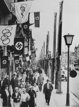 A street scene showing displays of the Olympic and German (swastika) flags in Berlin, site of the summer Olympic Games. [LCID: 76499]