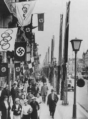 Utcakép, amelyen az olimpiai és német (horogkeresztes) zászlók láthatók Berlinben, a nyári olimpiai játékok helyszínén. Berlin, Németország, 1936. augusztus