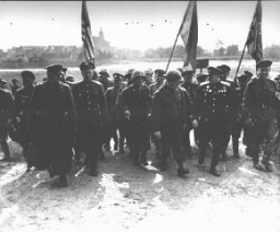 Members of the Soviet and US armed forces following their link-up at the Elbe River, east of Torgau. Americans crossed the river in small boats to meet the Soviet soldiers. Major General Emil F. Reinhardt of the 69th Infantry Division (3rd from right) speaks with with the commander of  the Soviet 58th Infantry Division (2nd from right). Germany, April 26, 1945.