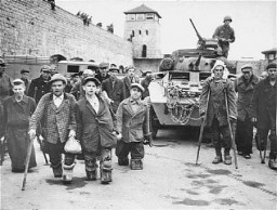 Soviet and Polish prisoners with disabilities stand in front of a tank of the 11th Armored Division, US Third Army. This photograph was taken at the Mauthausen concentration camp immediately after liberation. Austria, May 5–7, 1945.