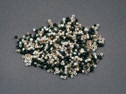 These tiny black, white, gold, and clear glass beads were used by Rachel “Chelly” de Groot from November 1942 to April 1944 and recovered by her brother Louis after the war. Chelly used the beads to make handicrafts.
On November 16, 1942, Chelly, then 15, Louis, 13, and their parents Meijer and Sophia left Arnhem and went into hiding after the Dutch police warned them of a raid. Meijer and Sophia hid in Amsterdam while Chelly and Louis moved around to different locations. In summer or fall 1943, Chelly went to Amsterdam to live with her parents. In December, Louis was sent to Lemmer to live with the Onderweegs family.
In February 1944, Dirk Onderweegs offered to take Chelly to a safer hiding place. But on April 8, 1944, four days before Dirk was to return, Chelly and her parents were denounced and arrested. They were sent to Westerbork transit camp, then to Auschwitz. Chelly and Sophia were killed upon arrival in Auschwitz on May 22, 1944. Meijer was selected for a work detail and was killed later on September 30, 1944. 
Louis remained in hiding with the Onderweegs until liberation in mid-April 1945.