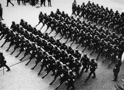 Members of the SS (Schutzstaffel; originally Hitler's bodyguard, later the elite guard of the Nazi state) parade during a rally. [LCID: 86520]