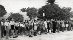 Des enfants se tiennent au garde-à-vous lors d'une cérémonie du drapeau à la colonie d'été d'Ayindram Betar. Tunisie, 1946. 
 