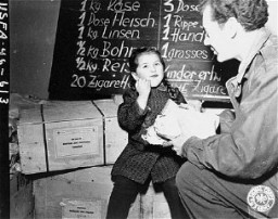 Harry Weinsaft of the American Jewish Joint Distribution Committee gives food to a young Jewish refugee. Vienna, Austria, postwar.