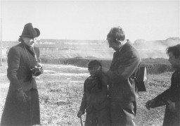 Dr. Robert Ritter and Eva Justin examine a young boy interned in a Zigeunerlager (“Gypsy camp”). Cologne, Germany, c. 1937-1940.
During the Nazi era, Dr. Robert Ritter was a leading authority on the racial classification of people pejoratively labeled “Zigeuner” (“Gypsies”). Ritter’s research was in a field called eugenics, or what the Nazis called “racial hygiene.” Ritter worked with a small team of racial hygienists. Among them were Eva Justin and Sophie Ehrhardt. Most of the people whom Ritter studied and classified as Zigeuner were German Roma called Sinti. Sinti are a subgroup of Romani peoples. 
In 1935, municipal authorities across Nazi Germany began to force Romani families to move into Zigeunerlager (“Gypsy camps”). Eventually, these camps were centralized under the authority of the Nazi Kripo (criminal police). Ritter and his team regularly examined the individuals in these camps. They sometimes used threats or bribes to force people to cooperate. The creation of these camps was one of the Nazis’ early steps toward the genocide of Romani peoples. Many Romani victims were later deported to concentration camps, ghettos, or killing centers. 
Source Record ID: Bild 146-1987-107-30