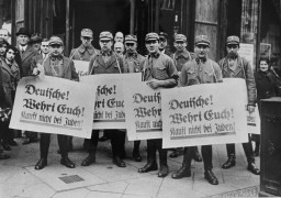 During the anti-Jewish boycott, SA men carry banners which read "Germans! [LCID: 12359]