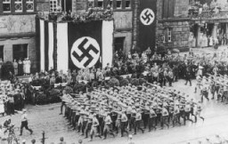 Bataillons de combattants de rue nazis saluant Hitler au cours d’un défilé des SA (Sturmabteilung, section d’assaut) dans les rues de Dortmund. Allemagne, 1933.