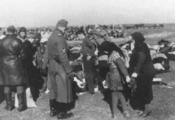 Ukrán zsidók, akiket Einsatzgruppe-osztagok vetkőzésre kényszerítettek, mielőtt lemészárolták őket. Ez az eredetileg színes fénykép egy német katonai fényképész által készített sorozat része. A gyűjteményből készített másolatokat később bizonyítékként használták fel a háborús bűnösök pereiben. Lubni, Szovjetunió, 1941. október 16.