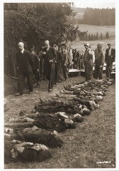 تحت مراقبة أطباء أمريكان يقوم مدنيون ألمان بتكديس جثث يهوديات تم اخراحها من مقبرة جماعية في فولاري. لقى الضحايا حتفهم عند نهاية مسير ات الموت من هلمبريختس, محتشد فرعي لفلوسنبورغ. فولاري, تشيكسلوفاكيا, 11 مايو 1945.