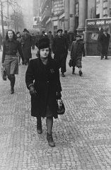 Elsa Eisner, marked with a Jewish badge, walks down a street in Prague. She, her mother, twin sister and other members of the family were deported to Auschwitz in July 1942. Prague, Czechoslovakia, ca. 1941.