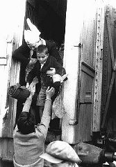 A nurse helps one of the "Tehran Children," Polish Jewish refugees, disembark from a train at the Atlit refugee camp. Atlit, Palestine, February 18, 1943.