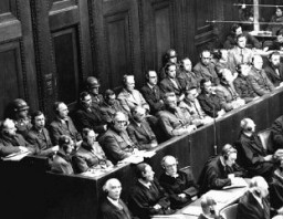  Defendants seated under guard in the defendants' dock, behind the defense counsel, during the Doctors' Trial. [LCID: 07355]