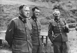 This photograph shows a group of SS officers at Solahütte, the SS retreat outside of Auschwitz. Pictured from left to right: Richard Baer, Dr. Josef Mengele, and Rudolf Höss.
From Karl Höcker's photograph album, which includes both documentation of official visits and ceremonies at Auschwitz as well as more personal photographs depicting the many social activities that he and other members of the Auschwitz camp staff enjoyed. These rare images show Nazis singing, hunting, and even trimming a Christmas tree. They provide a chilling contrast to the photographs of thousands of Hungarian Jews deported to Auschwitz at the same time.