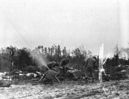 Des servants de mortier du 754e du bataillon d'artillerie lancent un obus de mortier de 81 mm sur des positions allemandes au cours de combats acharnés dans la forêt de Hürtgen. 15 décembre 1944. Corps de transmission de l'Armée américaine, photographie prise par C. Tesser.
