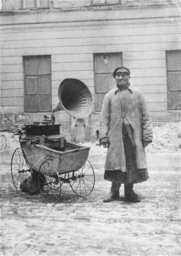 A Jewish man attempts to make a living by playing music on a gramophone, which he wheels around in an old baby carriage. [LCID: 66813]