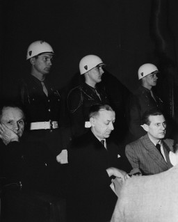 Defendants Karl Doenitz (left), Erich Raeder (center), and Baldur von Schirach under guard in the defendants' dock at Nuremberg. [LCID: 10386]