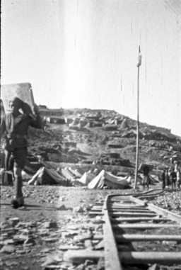 Un ouvrier non identifié marche le long des rails au camp de travail d'Im-Fout, au Maroc. Les conditions de vie étaient pénibles dans le camp et beaucoup de travailleurs y attrapaient le typhus. Im-Fout, Maroc, 1941-42. 