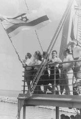 Jewish refugee children unfurl the Zionist flag as they arrive at the Haifa port aboard Aliyah Bet ("illegal" immigration) ship SS Franconia. Palestine, September 1945.